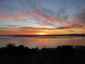 a sunset over a large body of water at Kestrel, Longhouse Cottages in Rosemarkie