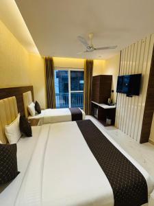 a hotel room with two beds and a television at Hotel Hrishikesh High Tapovan in Rishīkesh