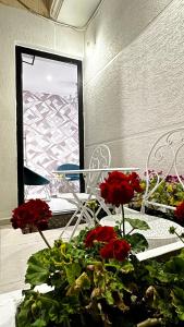 a room with a table with red flowers and chairs at Ajsel Luxury Rooms in Sarandë