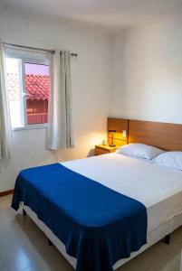 a bedroom with a large bed with a blue blanket at Hostel X20 in Arraial do Cabo