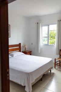 a bedroom with a large white bed and a window at Hostel X20 in Arraial do Cabo