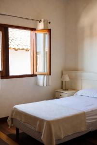 a bedroom with a white bed and a window at Hostel X20 in Arraial do Cabo