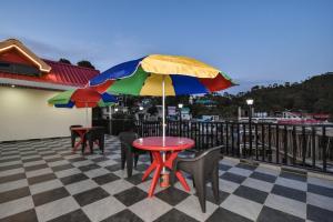 a table with a colorful umbrella on a patio at Hotel Dalhousie Delight in Dalhousie