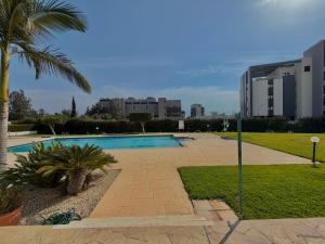 a swimming pool in a park with a palm tree at Bayview Terraces Cozy 1BR Haven in Limassol +4 photos