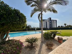 a swimming pool with a palm tree and a building at Bayview Terraces Cozy 1BR Haven in Limassol