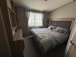 a small bedroom with a bed and a window at Hardys Caravan Park in Ingoldmells