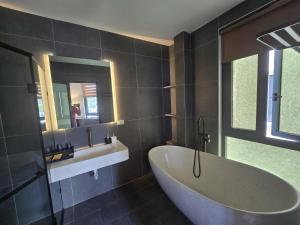 a bathroom with a large tub and a sink at DOS GATOS Hotel in Ðố Sơn