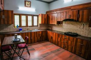 a kitchen with wooden cabinets and a table with chairs at Athira Homestay in Kollengode