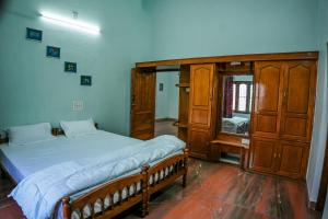 a bedroom with a bed and a wooden cabinet at Athira Homestay in Kollengode +17 photos