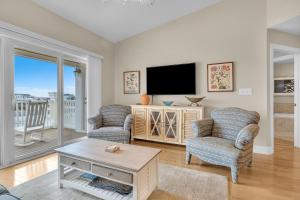 a living room with two chairs and a flat screen tv at Mystic Shore in Oak Island