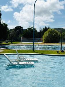 two white chairs sitting in a pool of water at Iloa Residence V13 Beach - localização privilegiada in Barra de São Miguel +10 photos