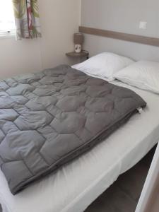 a bed with a gray blanket on top of it at Mobil-home Moon River in Thiviers