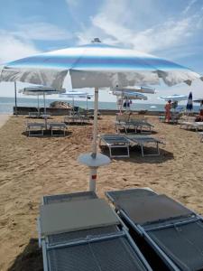 a group of chairs and an umbrella on the beach at BeaMare - Monolocale - Massimo tre ospiti con posto spiaggia - Studio Apartment - Max 3 people with 1 private umbrella and two SunBeds at the private beach of Eraclea Mare in Eraclea Mare