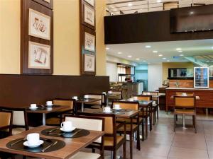 a restaurant with wooden tables and chairs and a kitchen at Flat Mercure Nova Iguaçu in Nova Iguaçu