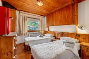 a bedroom with two beds and a window and wooden walls at Affittacamere De Charme Jour Et Nuit in Torgnon