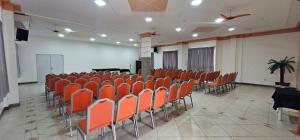 an empty room with orange chairs and a stage at Esplendor Palace Hotel in Vitória da Conquista