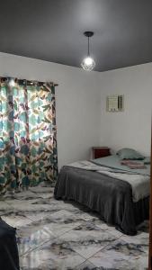 a bedroom with a bed and a window with curtains at Morada Iluminada Aconchego com Ar condicionado e Lareira in Miguel Pereira