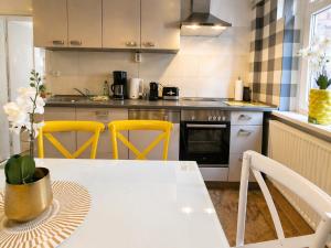 a kitchen with a white table and yellow chairs at Gemütliches Apartment am Bad Muskauer Park Sauna zu buchbar Hunde willkommen Ruhige Lage in Bad Muskau