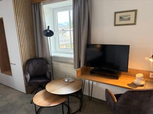 a room with a desk with a television and a chair at Pension Schiessling in Anif +8 photos