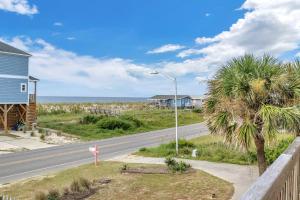 a road in front of a house and a palm tree at No Worries in Oak Island