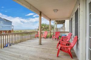 a porch with red chairs and a table on it at No Worries in Oak Island