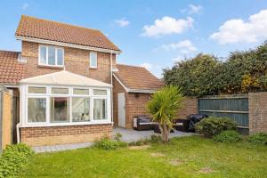 a brick house with a large window and a patio at Shell Seekers - Selsey in Selsey