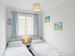 two beds in a room with a window at Shell Seekers - Selsey in Selsey