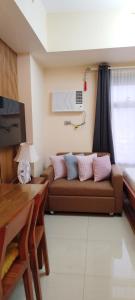 a living room with a brown couch with pink pillows at The Radiance Manila Bay Studio 2 in Manila