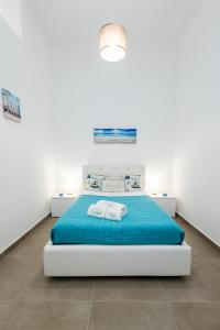 a white bedroom with a blue bed in a room at La Casetta al mare in Balestrate