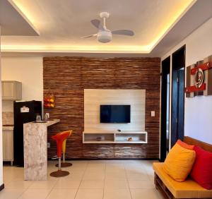 a living room with a tv on a brick wall at Hotel Natal Ponta Negra Sun in Natal