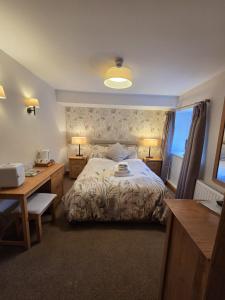 a bedroom with a bed and a desk with two lamps at Royal Oak Braithwaite in Keswick