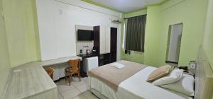 a bedroom with a bed and a desk and a kitchen at Esplendor Palace Hotel in Vitória da Conquista +34 photos