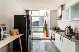 a kitchen with a black refrigerator and a window at Casa Reforma by Kukun in Mexico City +9 photos