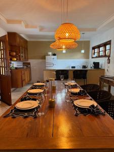 a large wooden table with plates and wine glasses at Chácara com Piscina, Hidro, Campo de futebol, Beach Tennis, Sinuca e Churrasqueira in Analândia