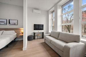 a white living room with a couch and a tv at Le Nomade Quartier Chinois in Montreal