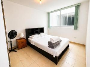 a bedroom with a bed with white sheets and a window at Departamento Harmony Xalapa in Xalapa