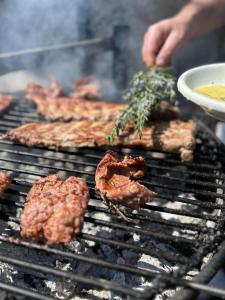 a person cooking meat on a barbecue grill at Relax alpino con sauna - Ca da Viola in Cavagnago