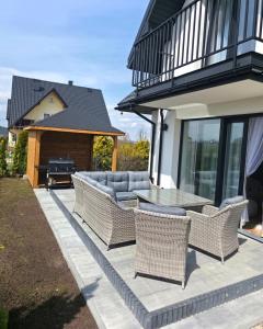 a patio with wicker chairs and a table and a grill at Markowicz Alpine House in Szaflary