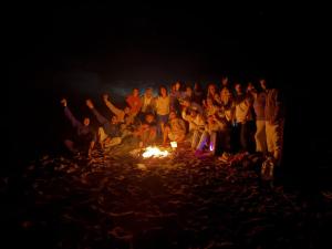 a group of people standing around a fire at night at Swellora Surf Camp Imsouane in Imsouane