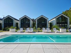 a swimming pool with chairs and a building at NOVA ULINIA Sea - dom nad morzem, podgrzewany basen, sauna, balia z jacuzzi,Starlink in Ulinia
