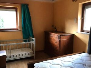 a bedroom with a crib and a dresser and window at Maison Schmidt in Oderen