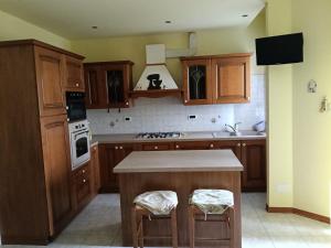 a kitchen with wooden cabinets and a kitchen island with stools at Casa Sofia in Marina Julia