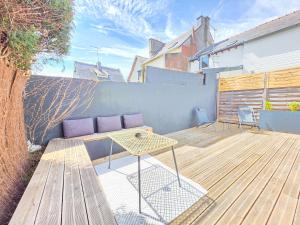 a patio with a table and a couch on a wooden deck at Le Sauge, 5 min Gare, Terrasse, Stationnement in Saint-Brieuc