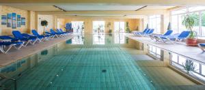 uma piscina com cadeiras azuis e uma piscina em Nordseehotel Freese em Juist