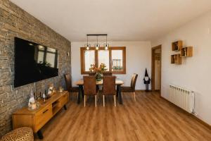 a living room with a dining room table and a brick wall at El Rincón del Pirineo l WIFI l GARAJE l VISTAS in Senegüé