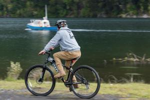 a man riding a bike by a body of water at Refugio PARQUE NACIONAL ALERCE ANDINO in Puerto Montt