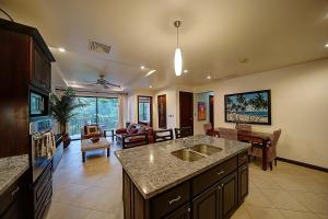 a kitchen with a sink and a living room at Monaco Condominiums in Jacó