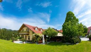 a house on a green lawn with a tree at Apartmaji Smogavc in Zreče +19 photos