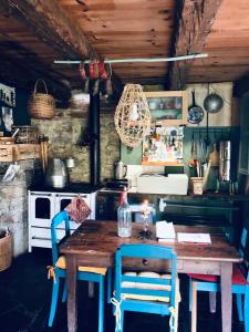 a kitchen with a wooden table and blue chairs at VeNeZ DoRmiR dans notre Bergerie au Cœur des Pyrénées Hebergement atypique in Bordères-Louron +63 photos
