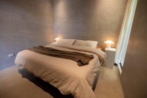 a bedroom with a large bed with two lights on it at Garden Treehouse Ikhaya in Refundores